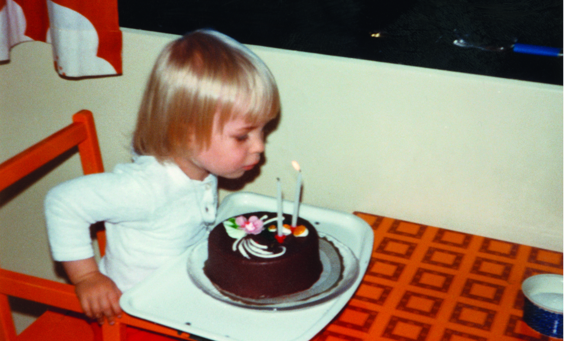 Tyttö puhaltaa 2-vuotissyntymäpäiväkakun kynttilöitä.